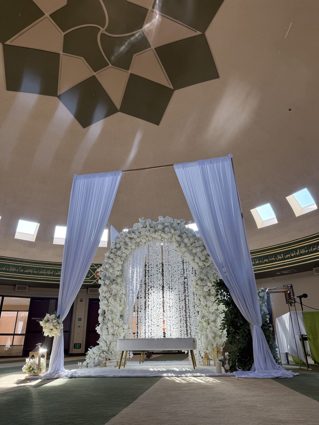 A flower arch with draped fabric under the masjid dome